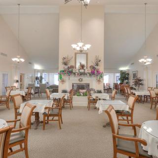 Elegant dining area with neatly arranged tables and chairs, adorned with stylish decor and chandeliers.