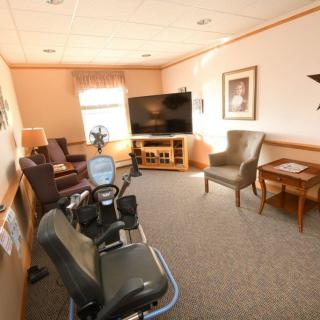 A cozy living room with chairs, a television, and exercise equipment.