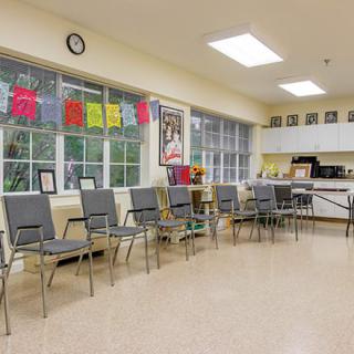 An empty waiting room with a row of chairs and large windows letting in daylight.