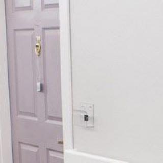 A hallway with a closed door and a light switch on the wall.