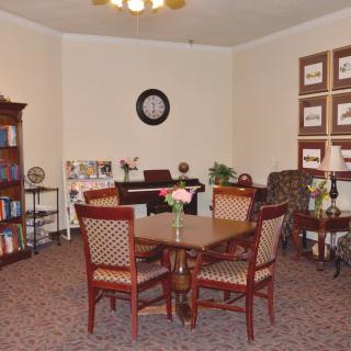 A cozy living room with a round table, chairs, and a bookshelf.