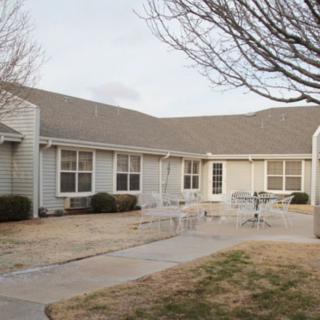 A residential building with a patio and outdoor furniture in the yard.