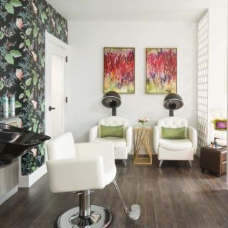 A stylish salon interior with modern chairs, vibrant artwork, and floral wallpaper.