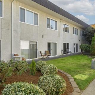 A two-story apartment building with a well-maintained lawn and garden area.