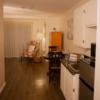 A cozy apartment interior featuring a modern kitchen and living area with wood flooring.