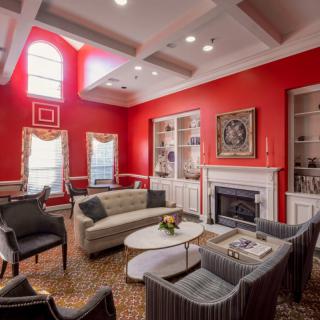 A cozy living room with red walls, featuring comfortable seating arrangements and a fireplace.
