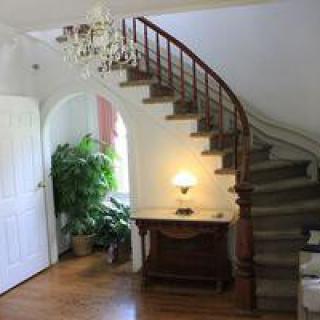 A cozy interior with a curved staircase, chandelier, and elegant decor.
