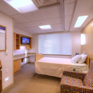 A modern and clean hospital patient room, equipped with essential furnishings and natural light.