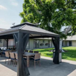 A stylish gazebo with outdoor furniture set in a spacious garden area.
