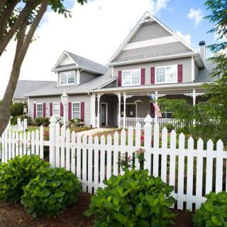 A charming Victorian-style house with a white picket fence and well-maintained garden.