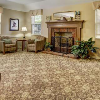 A cozy living room with a patterned carpet and a fireplace.