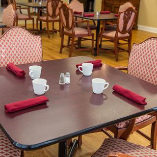 A dining table set up with red napkins and coffee cups, ready for guests in a restaurant.