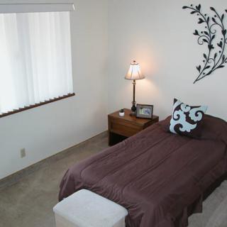 A cozy bedroom with a single bed, nightstand, and decorative wall art.