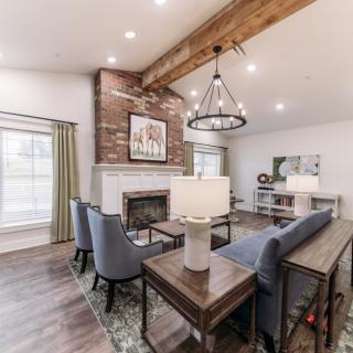 A modern living room featuring a large fireplace, wooden beam ceiling, and stylish furniture.