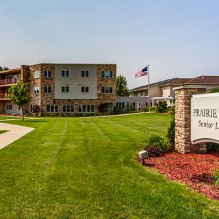 A senior apartment complex with a well-maintained green lawn and an American flag displayed outside.