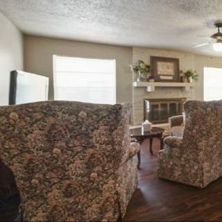 A cozy living room with floral armchairs and a fireplace.