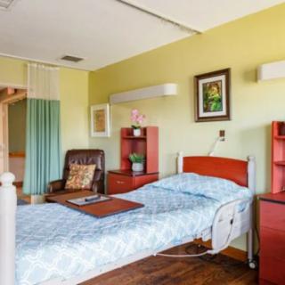A well-lit hospital room with a single bed and comfortable seating.