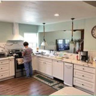 A person cooking in a modern kitchen with white cabinets and appliances.
