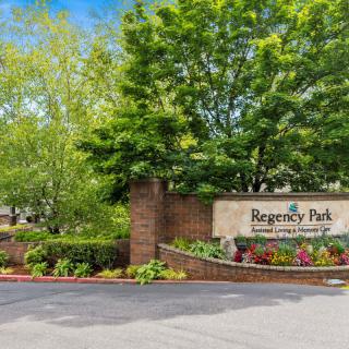 Entrance to Regency Park surrounded by lush landscaping and trees.