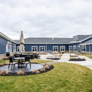 A peaceful courtyard featuring outdoor seating surrounded by modern architecture under a cloudy sky.