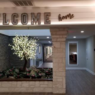A warm and inviting home entrance featuring a lit decorative tree and a 'Welcome Home' sign.