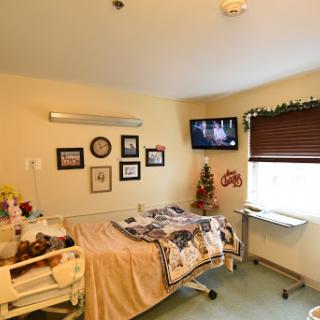 A cozy hospital patient room featuring a bed, decorated walls, and a television.