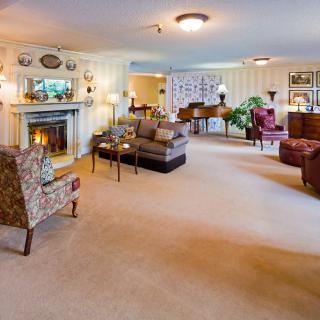 A spacious and cozy living room with a fireplace, piano, and elegant furniture.
