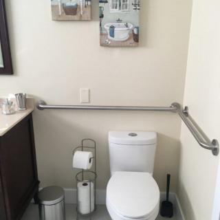 A bathroom with a toilet, safety grab bars, and various accessories.