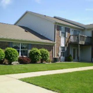 A suburban residential building with a well-maintained lawn and a balcony.