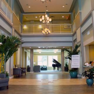 A spacious lobby with a chandelier, grand piano, and comfortable seating.