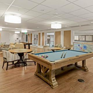 A well-lit game room featuring a pool table and seating area.