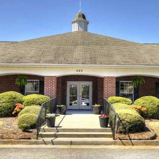 A brick building with a central entrance surrounded by landscaped shrubs.