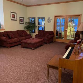 A cozy living room with a set of sofas, a piano, and warm decor.