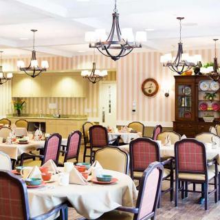 An elegantly decorated restaurant dining room with neatly arranged tables and chairs, adorned by chandeliers.