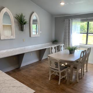 A cozy, modern dining area featuring a wooden table and chairs, complemented by elegant mirrors and natural lighting.