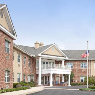 A brick building with a columned entrance and an American flag at the front.