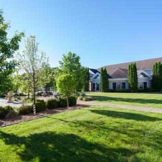 A scenic view of a building surrounded by lush greenery and trees on a sunny day.