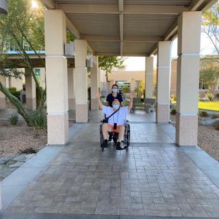 Two friends enjoying a walk together, with one in a wheelchair.