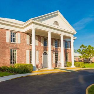 A brick building with colonial architecture featuring large columns and a clear blue sky.