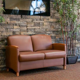 A cozy brown leather sofa against a textured stone wall, complemented by indoor plants.