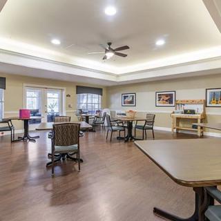 A well-lit dining area with tables and chairs arranged neatly, featuring minimalist decor.