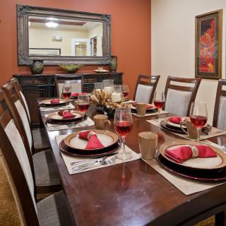 A beautifully set dining room table with red napkins and wine glasses.