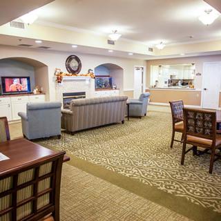 A cozy communal living area with comfortable seating, a fireplace, and a television.