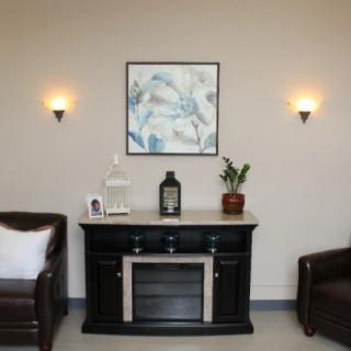 A stylish living room interior featuring a dark cabinet with decor, flanked by two leather chairs and illuminated by wall sconces.