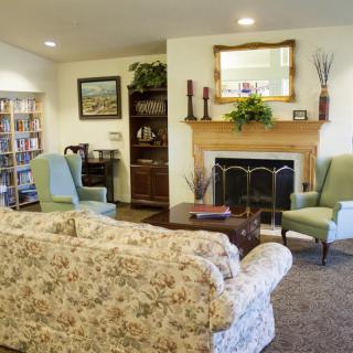 A cozy living room with a fireplace, armchairs, and a floral couch.