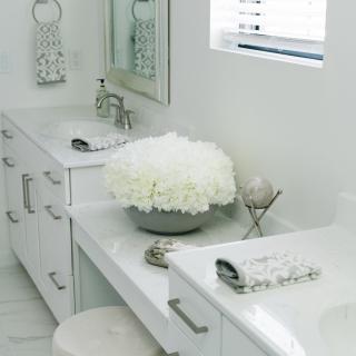 A modern white bathroom with elegant decor and fresh flowers.