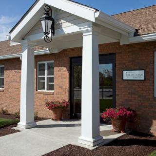 Entrance of a brick building with white columns and a hanging lantern.