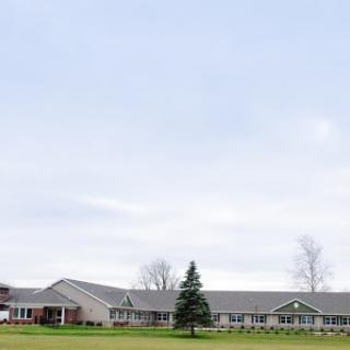 A modern residential building set against a cloudy sky, surrounded by greenery.
