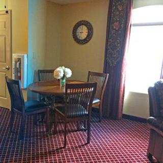 A cozy dining area with a round table, chairs, and decorative flowers near a window.