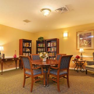 A cozy indoor reading area with bookshelves, a table, and chairs.